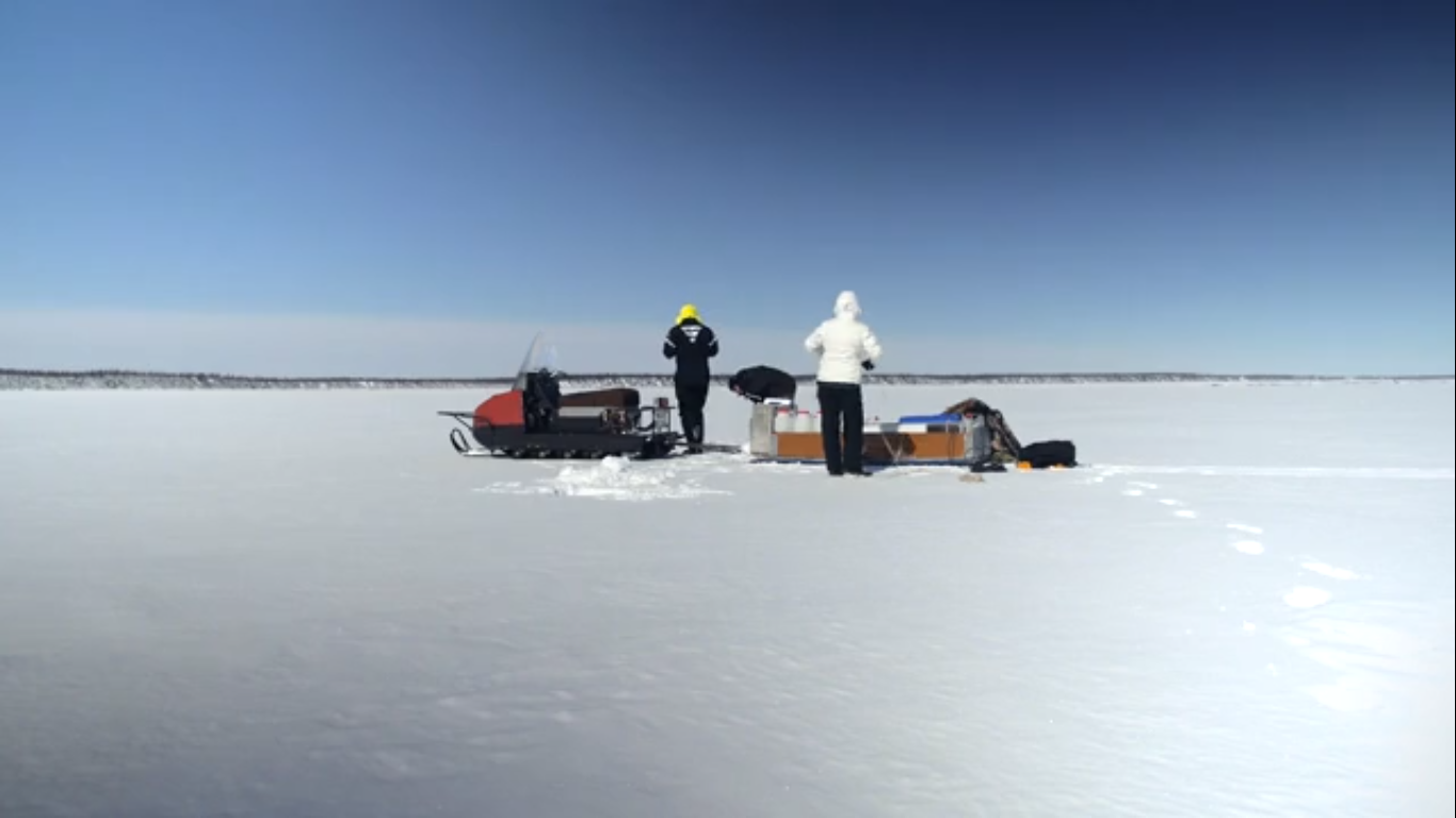 Deux personnes avec des caisses et un glisseur au milieu d'une grande étendue de glace