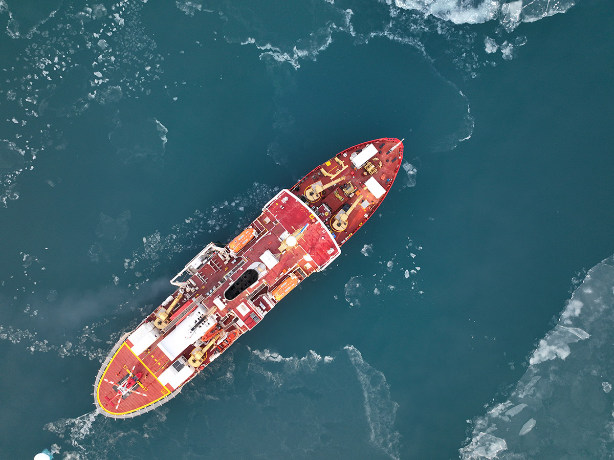 un brise-glace rouge vu de dessus (via un drone) sur fond de mer bien bleu