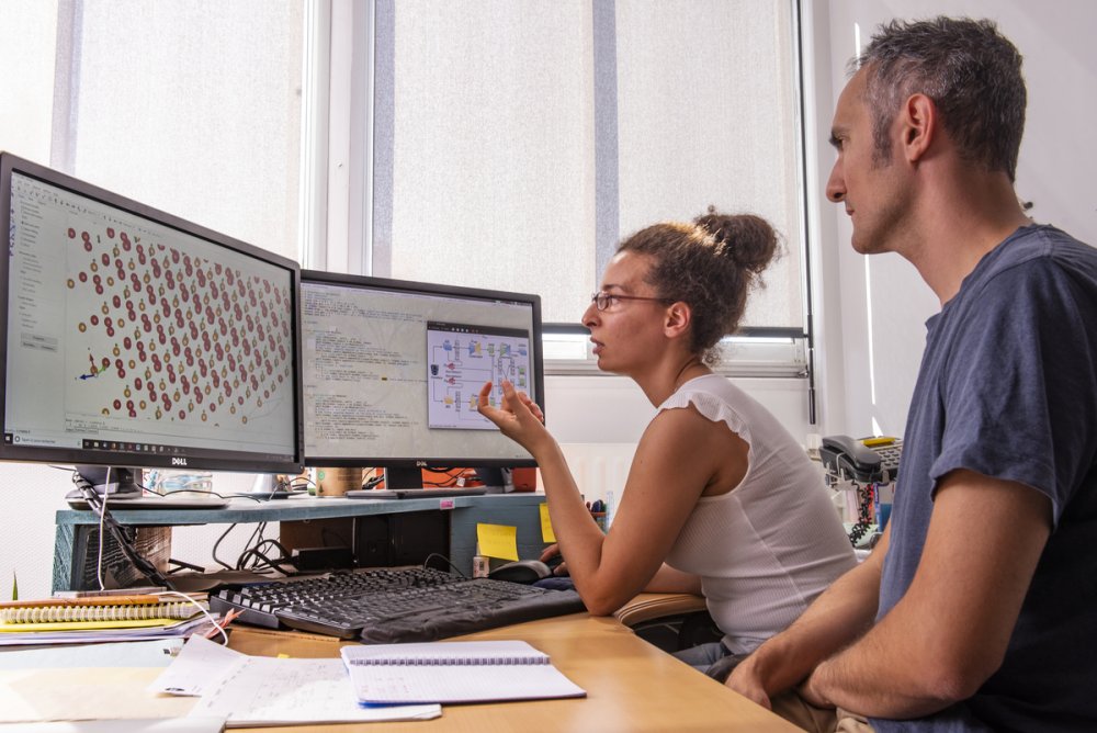 Un chercheur et une chercheuse face à un écran sur lequel apparaissent des simulations de molécules