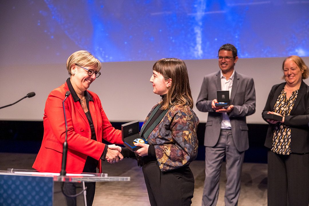 Sylvie Retailleau donnant sa médaille à une lauréate, les deux femmes souriant