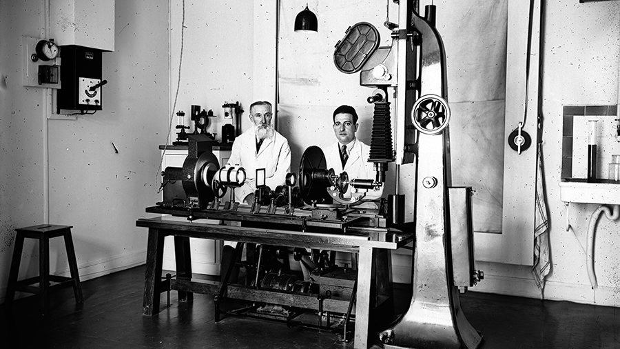 Le docteur Comandon et son assistant M. Pierre de Fonbrune, derrière le microcinématographe