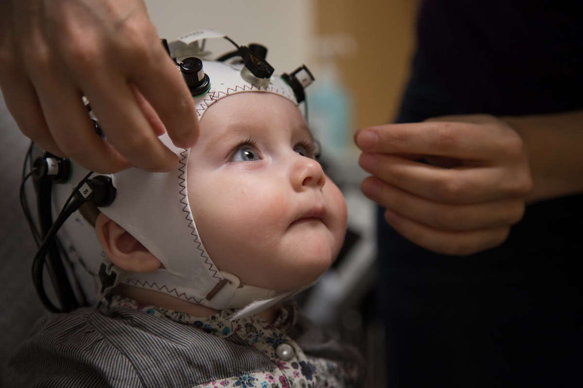 Bébé de 6 mois avec un casque en tissu muni d'électrodes sur la tête