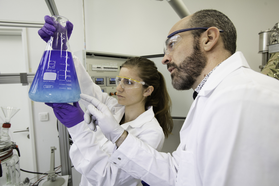 Deux chimistes, une femme et un homme, observant une réaction chimique dans une fiole appelée erlenmeyer