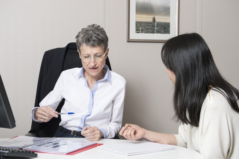 Two women converse during a work meeting around a table.