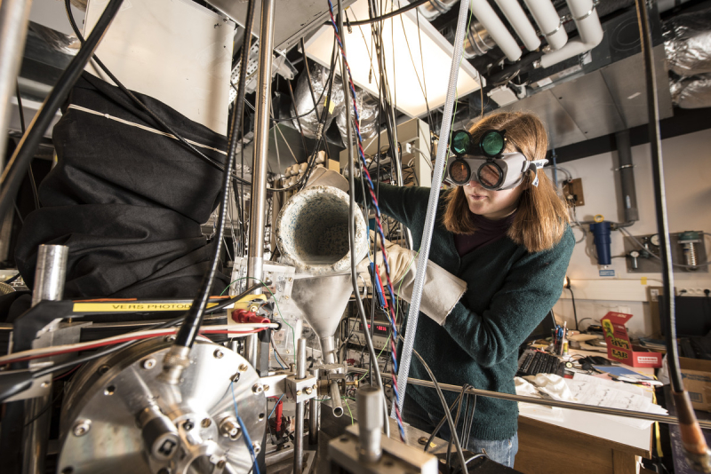 A woman pours liquid nitrogen into a vacuum chamber.