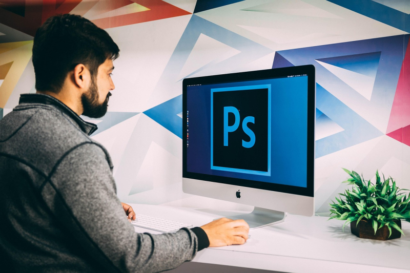A man is working on his computer using Photoshop