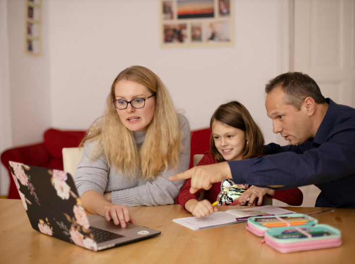 des parents regardent un écran d'ordinateur avec leur enfant