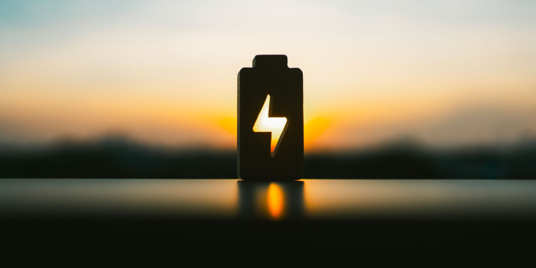 Une pile avec le symbole d'un éclair devant un coucher de soleil
