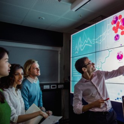 Homme faisant une démonstration devant un tableau numérique.
