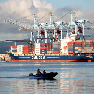 Une vedette passe devant un navire de l'armateur CMA-CGM dans le Grand Port Maritime de la Martinique.